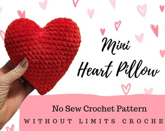Op de afbeelding: Een rood gehaakt hartvormig kussen met de tekst "Mini Heart Pillow" en "No Sew Crochet Pattern" eronder. De tekst "WITHOUT LIMITS CROCHET" staat onderaan de afbeelding.