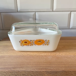May include: White glass baking dish with a clear glass lid. The dish features a floral design with orange and brown flowers on a white background.