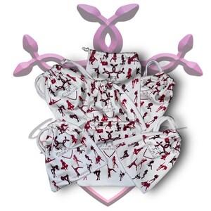 May include: Seven white drawstring bags with a red and white print of a woman's silhouette. The bags have the text "The Femme Fatale" printed on them.