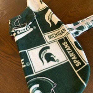 Puede incluir: Suéter de perro de franela verde y blanco con un patrón repetido del logotipo de los Spartans de Michigan State, incluyendo el casco Spartan, la palabra "Michigan" y la palabra "Spartans".