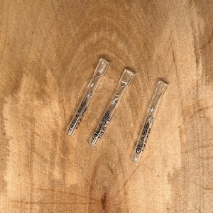 Può includere: Tre pipe da fumo in vetro trasparente con la scritta "GLASS MATE" stampata su di esse.