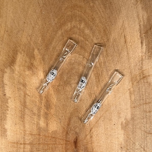 Può includere: Tre pipe da fumo in vetro trasparente con un design a faccia di cartone animato bianco.