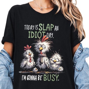 a woman wearing a black t - shirt that says today is slap an idiot day
