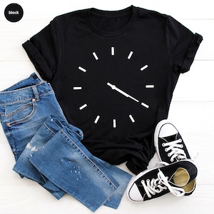May include: Black t-shirt with a white clock design. The clock has a single hand pointing to the right.