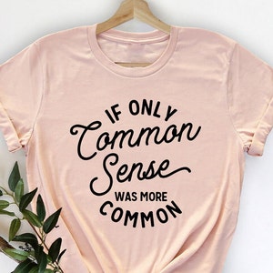 Peut inclure: Un t-shirt rose p&acirc;le avec un texte noir qui dit "Si seulement le bon sens &eacute;tait plus courant".