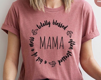 Può includere: Una maglietta rosa con una grafica circolare nera che dice "totalmente benedetta spesso stressata un po' di disordine mamma".