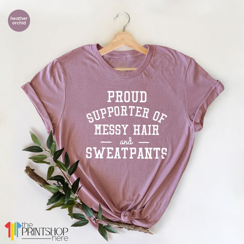 May include: A heather orchid t-shirt with the text "Proud Supporter of Messy Hair and Sweatpants" printed in white.