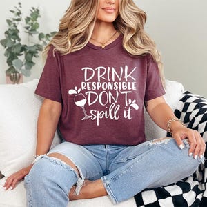 a woman sitting on a couch wearing a t - shirt that says drink responsible,