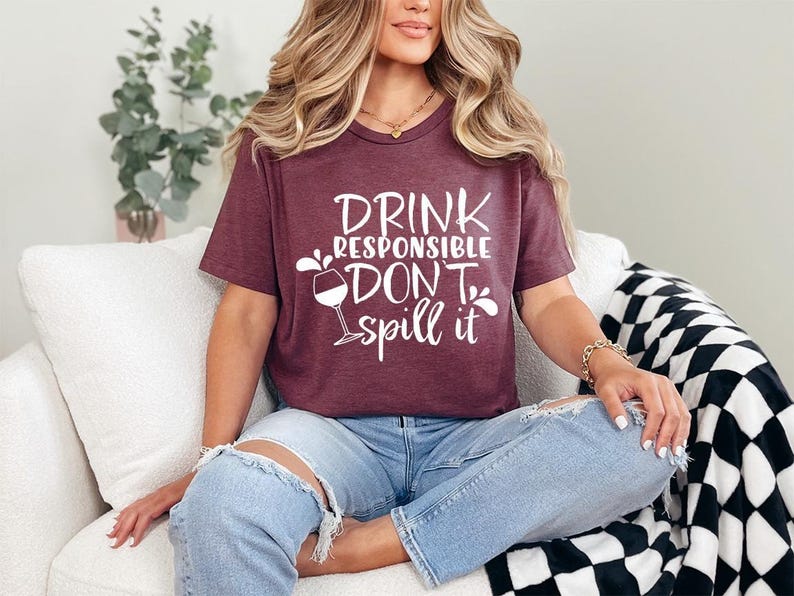 a woman sitting on a couch wearing a t - shirt that says drink responsible,
