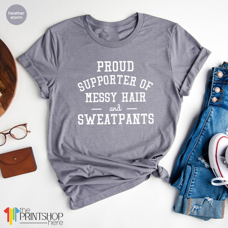 May include: Gray t-shirt with white text that reads "Proud Supporter of Messy Hair and Sweatpants".