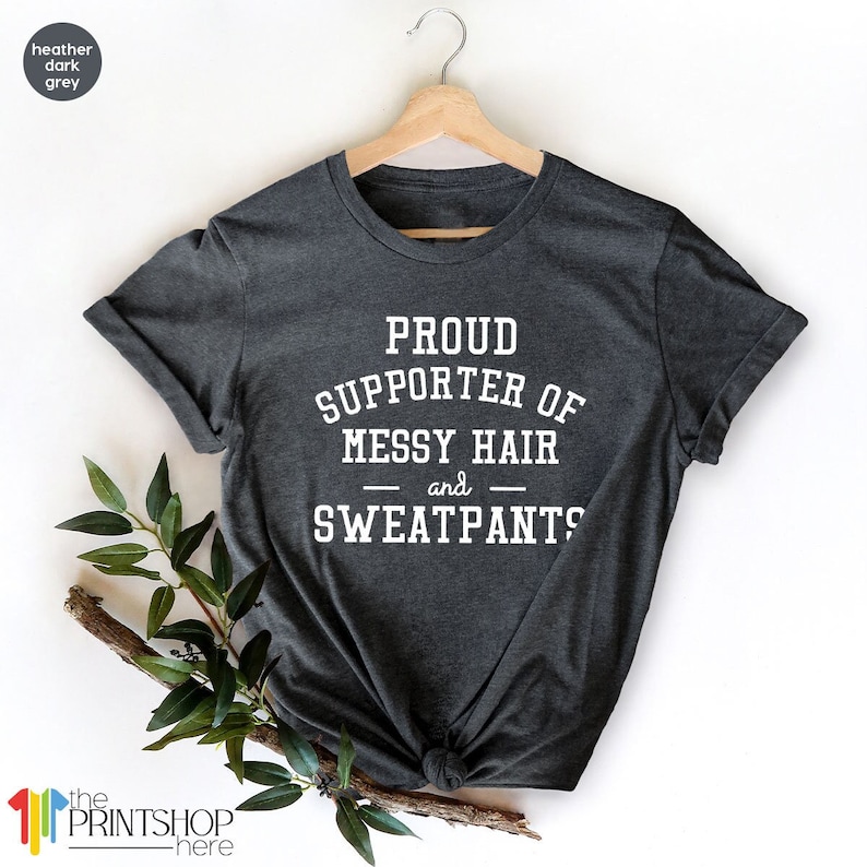 May include: A heather dark grey t-shirt with white text that reads "Proud Supporter of Messy Hair and Sweatpants".