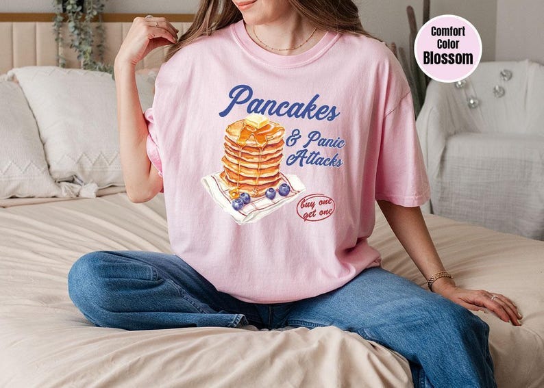 a woman sitting on a bed wearing a pink shirt
