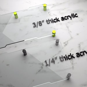 May include: Two clear acrylic sheets with black screws and yellow dots. The top sheet is labeled "3/8" thick acrylic" and the bottom sheet is labeled "1/4" thick acrylic".
