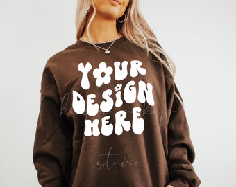 May include: A brown sweatshirt with the text "YOUR DESIGN HERE" in white, stylized lettering with a flower graphic.
