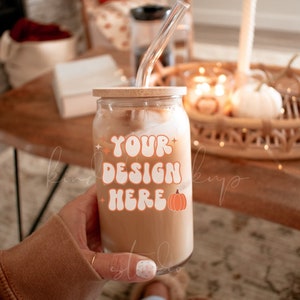 May include: A clear glass with a wooden lid and a reusable straw filled with a brown beverage. The glass has a sticker with the text "YOUR DESIGN HERE" and a small orange pumpkin graphic.