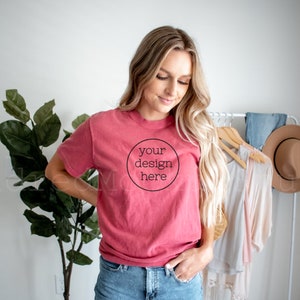 May include: A woman wearing a red t-shirt with the text "your design here" in a circle. She is wearing denim shorts and has her hand in her pocket.