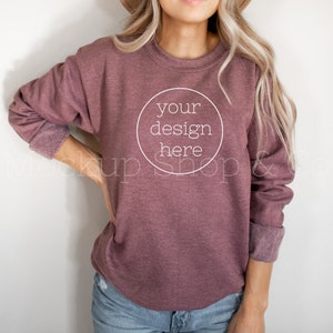 May include: A mauve colored sweatshirt with long sleeves and a crew neck. The sweatshirt has a white circle on the front with the text "your design here" inside.