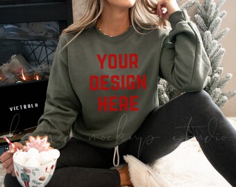 May include: A green sweatshirt with the text "YOUR DESIGN HERE" in red letters. The sweatshirt is being worn by a person sitting on a white fluffy rug.