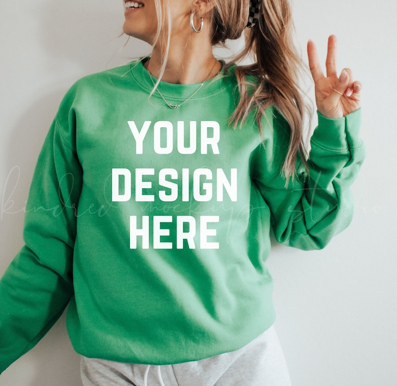 May include: A green sweatshirt with the text "YOUR DESIGN HERE" printed on the front.