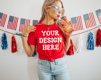 Könnte beinhalten: Eine Frau trägt ein rotes T-Shirt mit dem Text "YOUR DESIGN HERE" in Weiß. Sie hält ein Glas mit einem roten Getränk mit einem Strohhalm und trägt eine Sonnenbrille. Der Hintergrund ist eine weiße Wand mit einer rot-weiß-blauen Girlande.