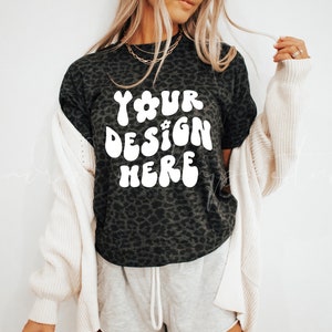 May include: A black t-shirt with a leopard print design. The shirt has white text that says "YOUR DESIGN HERE" in a retro font.