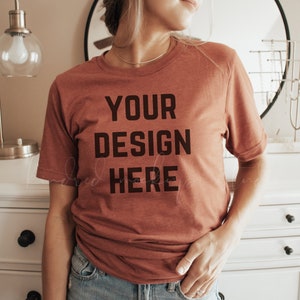 May include: A rust-colored t-shirt with the text "YOUR DESIGN HERE" printed in black.