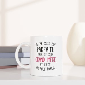 May include: White ceramic mug with a black and pink design. The text on the mug reads "Je ne suis pas parfaite mais je suis grand-m&egrave;re et c'est presque pareil".
