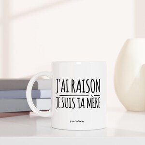 Puede incluir: Taza de cer&aacute;mica blanca con texto negro que dice "J'AI RAISON JE SUIS TA MERE" sobre una superficie blanca con una pila de libros y dos jarrones.