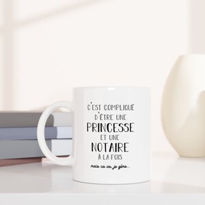 May include: White ceramic mug with black text that reads "C'EST COMPLIQUE D'&Ecirc;TRE UNE PRINCESSE ET UNE NOTAIRE A LA FOIS mais ca va je g&egrave;re..."