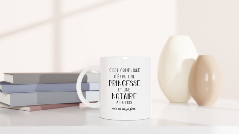 May include: White ceramic mug with black text that reads "C'EST COMPLIQUE D'&Ecirc;TRE UNE PRINCESSE ET UNE NOTAIRE A LA FOIS mais ca va je g&egrave;re..."