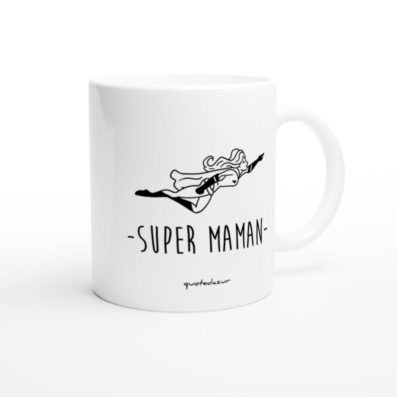 May include: White ceramic mug with a black line drawing of a woman flying with a cape and the text "SUPER MAMAN" below. The text "quotedezur" is at the bottom of the mug.