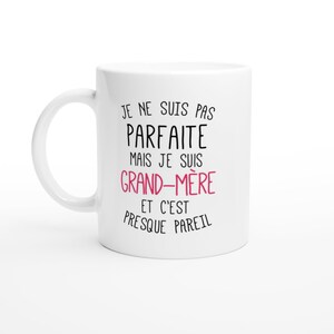 May include: White ceramic mug with black text that reads "Je ne suis pas parfaite mais je suis grand-m&egrave;re et c'est presque pareil". The word "grand-m&egrave;re" is in pink.