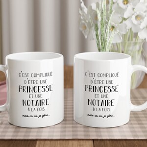 May include: Two white ceramic mugs with black text that reads "C'EST COMPLIQUE D'&Ecirc;TRE UNE PRINCESSE ET UNE NOTAIRE A LA FOIS mais ca va je g&egrave;re..."