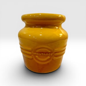 May include: A yellow ceramic jar with the word "MOUTARDE" embossed on the front. The jar has a rounded shape with a wide opening and a slightly textured surface. The jar is a mustard pot.