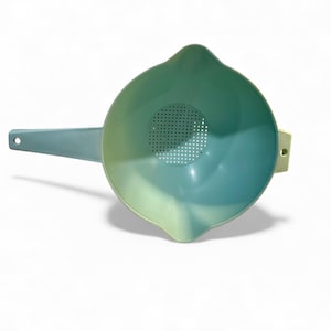 May include: A two-tone, teal and light green plastic colander with a handle and a pouring spout. The colander has a perforated bottom for draining liquids and a small handle on the side. The handle is a light teal color.