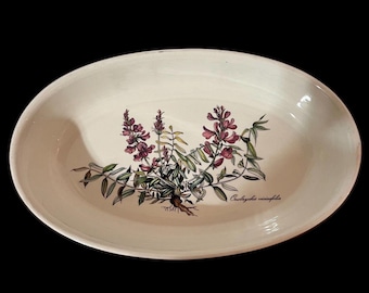 May include: White oval ceramic serving dish with a floral design featuring pink and green flowers and leaves. The text "Ononis spinosa" is printed on the dish.