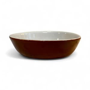 May include: A brown ceramic bowl with a white interior. The bowl has a rounded shape and a smooth, glossy finish. The exterior is a rich, dark brown color, while the interior is a clean white. The bowl is suitable for serving food.