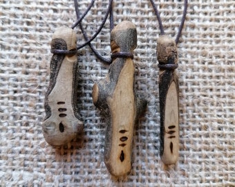 May include: Three wooden pendants with brown leather cords. Each pendant has a unique design with carved lines and a small hole at the bottom.