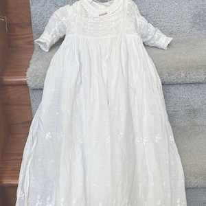 May include: A white ceramic mug with a black handle and the text "But First, Coffee" in a black, handwritten-style font. The mug is on a white surface.