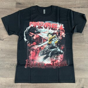 Op de afbeelding: Zwart T-shirt met een grafische print van personages uit de anime Attack on Titan. De grafiek toont een rode en witte achtergrond met de Japanse tekst "Shingeki no Kyojin" en de Engelse tekst "Attack on Titan".