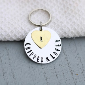 May include: Silver keyring with a round charm that says "Chipped & Loved" with a small gold heart charm with the letter "R" on it.