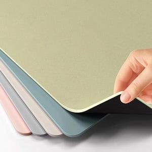 Puede incluir: Un juego de cinco manteles individuales en varios colores pastel, incluyendo rosa, gris y azul. Los manteles individuales están hechos de un material liso y texturizado y tienen un respaldo antideslizante negro.