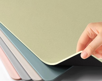 May include: A set of five placemats in various pastel colors, including pink, gray, and blue. The placemats are made of a smooth, textured material and have a black non-slip backing.