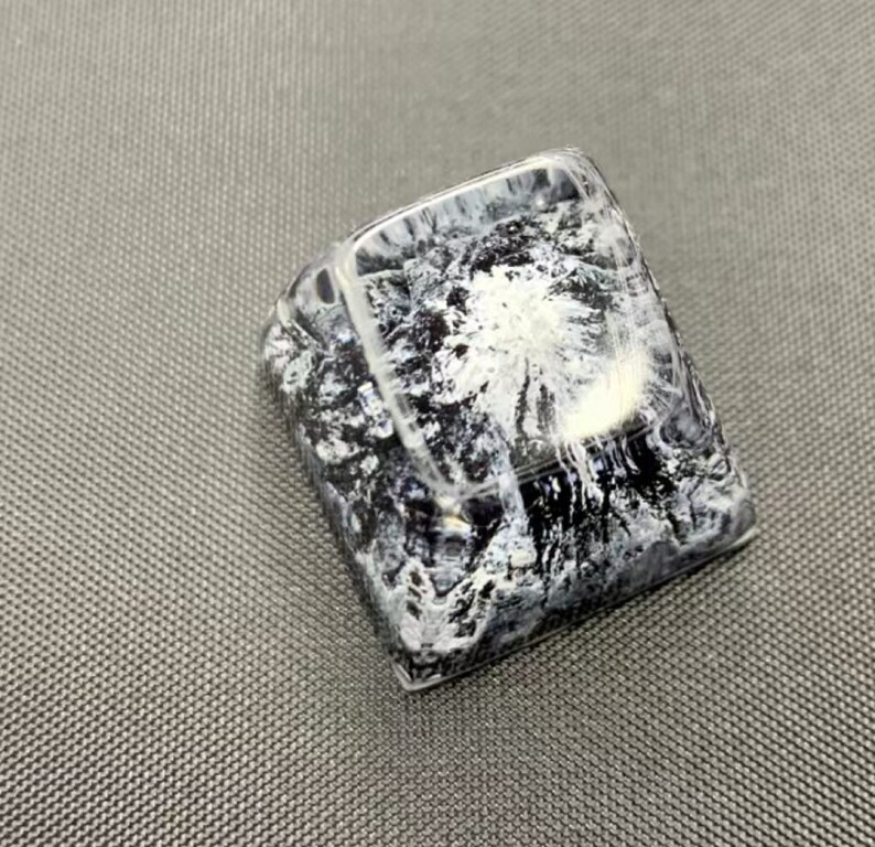 Pu&ograve; includere: Un keycap nero e bianco con un design astratto a spirale. Il keycap &egrave; realizzato in resina trasparente con un motivo nero e bianco incorporato all'interno.
