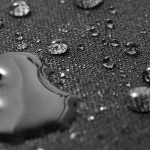 May include: Close-up of a dark grey fabric surface with water droplets, demonstrating the fabric's water-resistant qualities.