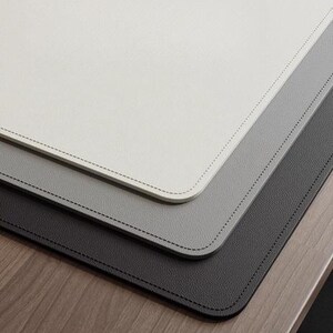 May include: Three layered desk mats in shades of grey, white, and black. The mats are made of a leather-like material and have a stitched edge.