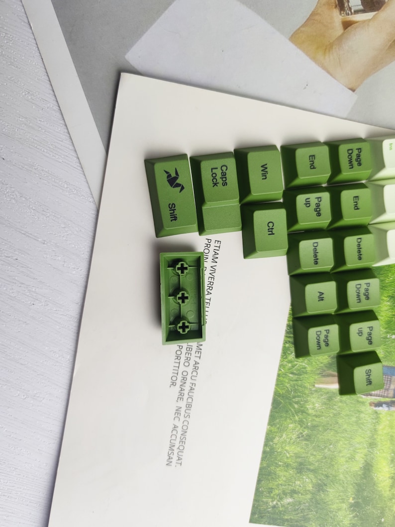 May include: Green mechanical keyboard keycaps with the words "Shift", "Caps Lock", "Win", "Ctrl", "End", "Page Up", "Page Down", "Delete", "Alt", "Page Up", "Page Down", and "Shift". The keycaps are arranged in a grid pattern. The keycaps are made of a green plastic material. The keycaps are designed to be used with a mechanical keyboard.