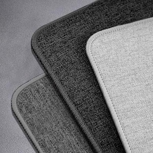 Op de afbeelding: Drie verschillende grijze en zwarte stofstalen met textuur. De stalen zijn gestapeld met het lichtste grijze staal bovenop en het donkerste grijze staal onderaan.