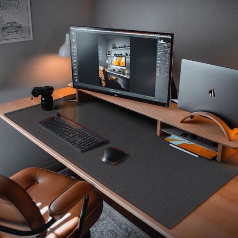 May include: A black desk mat with a textured surface, a keyboard, a mouse, and a laptop on a wooden desk.