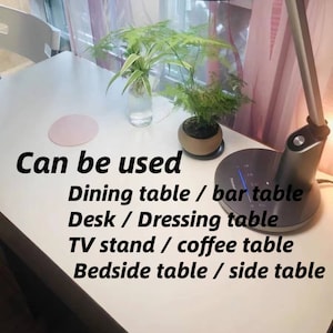 May include: A white table with a pink coaster, a potted plant, and a lamp. The text "Can be used Dining table / bar table Desk / Dressing table TV stand / coffee table Bedside table / side table" is written on the table.